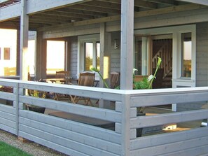 A wooden porch with a railing, a table, and chairs. - 2 bedroom accommodation in Fritton, near Great Yarmouth (Fritton, near Great Yarmouth)