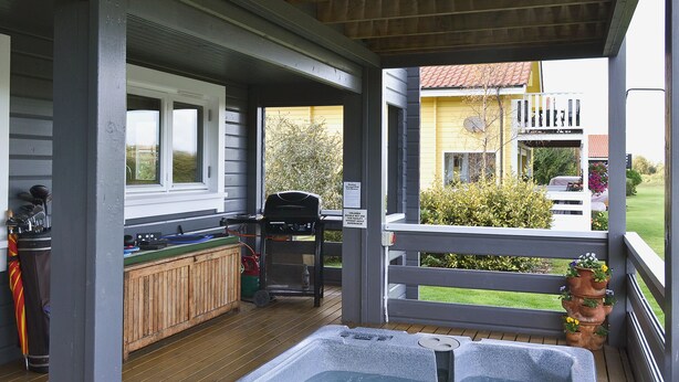 Un'area esterna coperta con vasca idromassaggio, barbecue e un patio in legno.