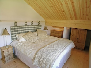 A bedroom with a bed, a nightstand, a dresser, and a wardrobe.