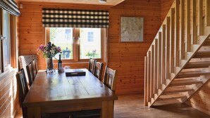 Un interno in legno con un tavolo da pranzo, sedie, un vaso con fiori, una mappa appesa al muro e una scala in legno.