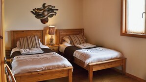 Una stanza con due letti di legno, una lampada a parete e una finestra con tende.