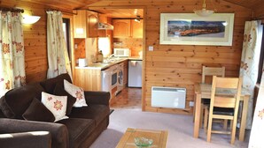 A cozy cabin interior with a sofa, a dining table, a kitchen area, and a framed picture on the wall. - 1 bedroom accommodation in Keswick (Keswick)