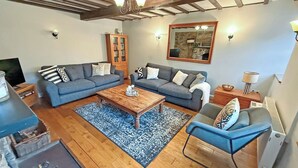 Un salon avec deux canapés, une table basse, un meuble en bois et un miroir au mur.