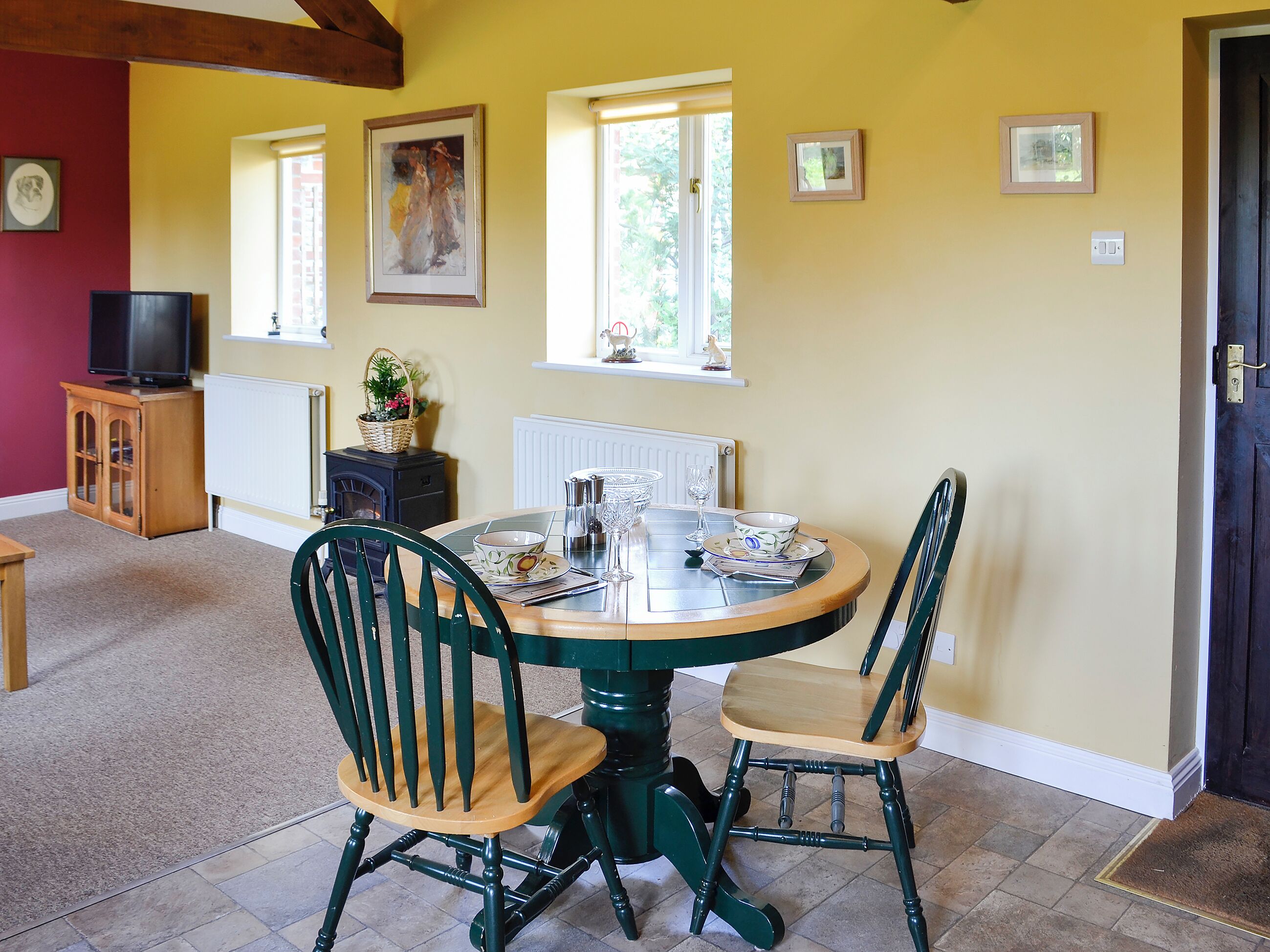 A dining area with a round table, two chairs, a television, and a fireplace.