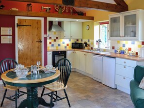 A kitchen with a dining table, chairs, a microwave, a sink, and cabinets.