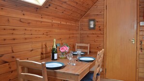 A wooden interior with a dining table set for two, a bottle of champagne, and a vase with flowers. - 2 bedroom accommodation in Blair Atholl near Pitlochry (Blair Atholl near Pitlochry)