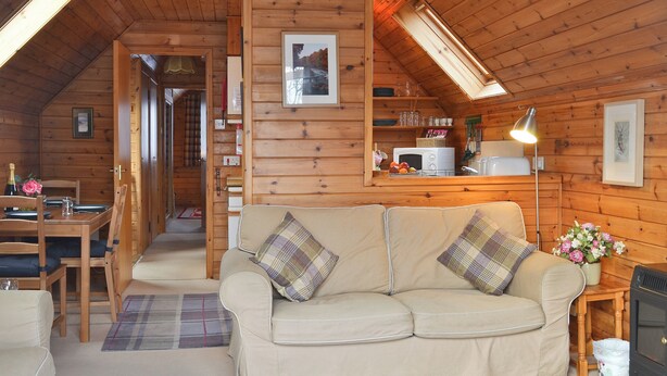 A cozy cabin interior with a sofa, dining table, and a kitchenette. - 2 bedroom accommodation in Blair Atholl near Pitlochry (Blair Atholl near Pitlochry)