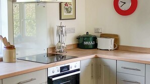 A kitchen with a stove, oven, and a wall-mounted clock. - 2 bedroom accommodation in Stanhoe, near King&rsquo;s Lynn (Stanhoe, near King&rsquo;s Lynn)