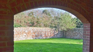 An arched brick structure with a well-maintained lawn and a stone wall in the background. - 2 bedroom accommodation in Stanhoe, near King&rsquo;s Lynn (Stanhoe, near King&rsquo;s Lynn)