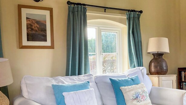 A white sofa with blue and white cushions, a lamp, and a framed picture on the wall. - 2 bedroom accommodation in Stanhoe, near King&rsquo;s Lynn (Stanhoe, near King&rsquo;s Lynn)