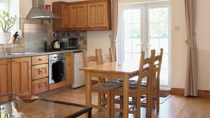 Une cuisine avec des meubles de rangement en bois, un four à micro-ondes, une cuisinière et une table à manger avec des chaises.