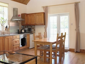 Una cocina con armarios de madera, microondas, estufa y una mesa de comedor con sillas.