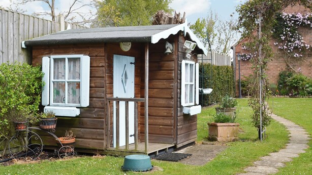 A small wooden cabin with a porch, a door, and windows.