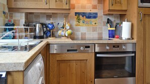 A kitchen with wooden cabinets, a dishwasher, an oven, and a tiled backsplash.