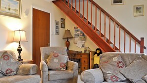 A living room with two armchairs, a wooden staircase, and a lamp.