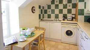 Une cuisine compacte avec un crédence à carreaux, un lave-linge et un coin repas comprenant une table et des chaises.