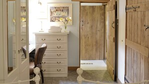 Una habitación con escritorio, silla, armario de madera y una puerta que da a otra estancia.