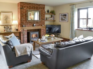 A living room with a fireplace, leather sofas, a television, and a bookshelf.