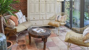 A cozy patio area with wicker furniture, a white cabinet, and a glass door leading to a garden. - 2 bedroom accommodation in Ilketshall St. Margaret, near Bungay (Ilketshall St. Margaret, near Bungay)