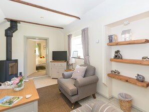 A cozy room with a sofa, a TV, a bookshelf, and a fireplace. - 1 bedroom accommodation in Thornton le Dale near Pickering (Thornton le Dale near Pickering)