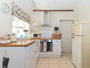 A compact kitchen with a microwave, oven, and refrigerator. There is a clock on the wall and a window with curtains. - 1 bedroom accommodation in Thornton le Dale near Pickering (Thornton le Dale near Pickering)