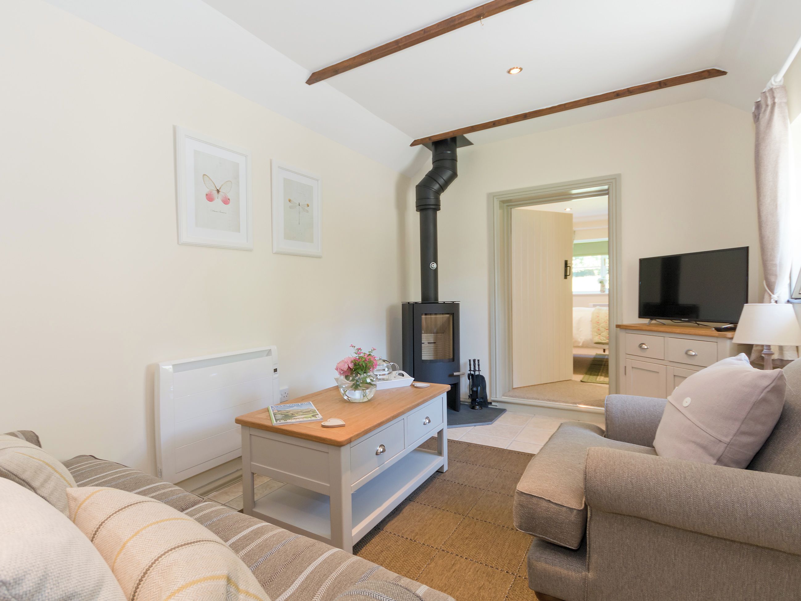 A living room with a sofa, a coffee table, a TV, a fireplace, and a door leading to another room.