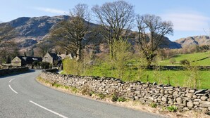 Un camino rural con muros de piedra y una casa de piedra.