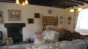Un salón tradicional con chimenea, muebles de estampado floral y una mesa de madera con sillas.
