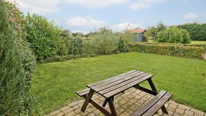 Une table de pique-nique dans une cour arrière verdoyante, avec une maison en arrière-plan.