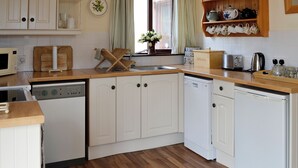 A kitchen with white cabinets, a wooden countertop, a microwave, a toaster, and a dishwasher.