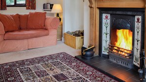 A cozy living room with a fireplace, a sofa, a rug, and a bookshelf.