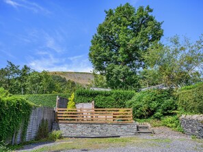 A stone wall with a wooden fence and a stone staircase leading up to a house.