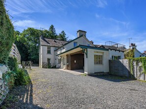 A two-story house with a gravel driveway and a wooden gate. - 5 bedroom accommodation in Keswick (Keswick)