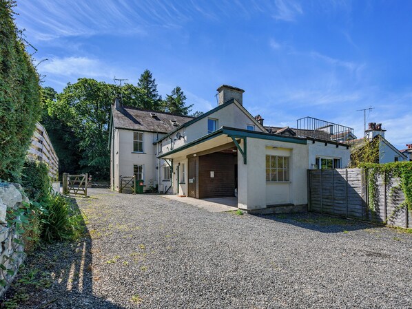 A two-story house with a gravel driveway and a wooden gate.