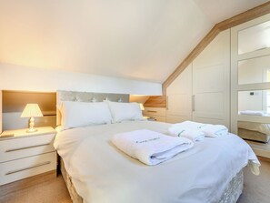 A bedroom with a large bed, bedside tables, a lamp, a wardrobe, and a mirror. - 5 bedroom accommodation in Keswick (Keswick)