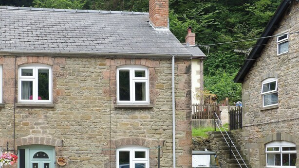 Un bâtiment en pierre avec une porte verte, de nombreuses fenêtres et un escalier menant à un étage supérieur.