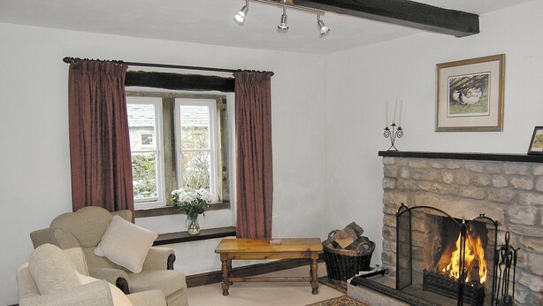 A cozy living room with a fireplace, a sofa, a bench, and a window with curtains. - 4 bedroom accommodation in Halton Gill, near Litton (Halton Gill, near Litton)
