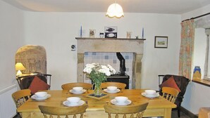 A dining room with a wooden table set for six, surrounded by wooden chairs. A vase with white flowers is placed in the center. - 4 bedroom accommodation in Halton Gill, near Litton (Halton Gill, near Litton)