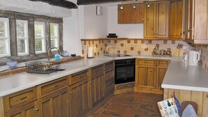 A kitchen with wooden cabinets, a tiled backsplash, and a window with a view of trees. - 4 bedroom accommodation in Halton Gill, near Litton (Halton Gill, near Litton)