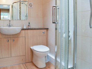 A modern bathroom with a glass shower enclosure, a white sink, and a toilet. - The Farriers - 26967 (St. Mary’s Park, Windermere)