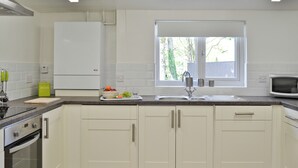 Cozinha moderna com armários brancos, pia de aço inoxidável e janela que traz luz natural.