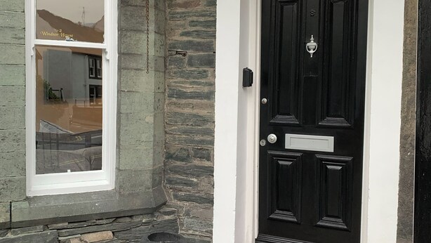 A black door with a brass knocker and a sign above it that reads "No 2 Windsor House". - 2 bedroom accommodation in Keswick (Keswick)