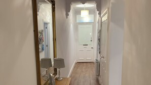 A hallway with a wooden bench, two lamps, a mirror, and a door at the end. - 2 bedroom accommodation in Keswick (Keswick)