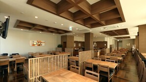 Een modern restaurant met houten meubels en een hoge plafond met zichtbare balken.
