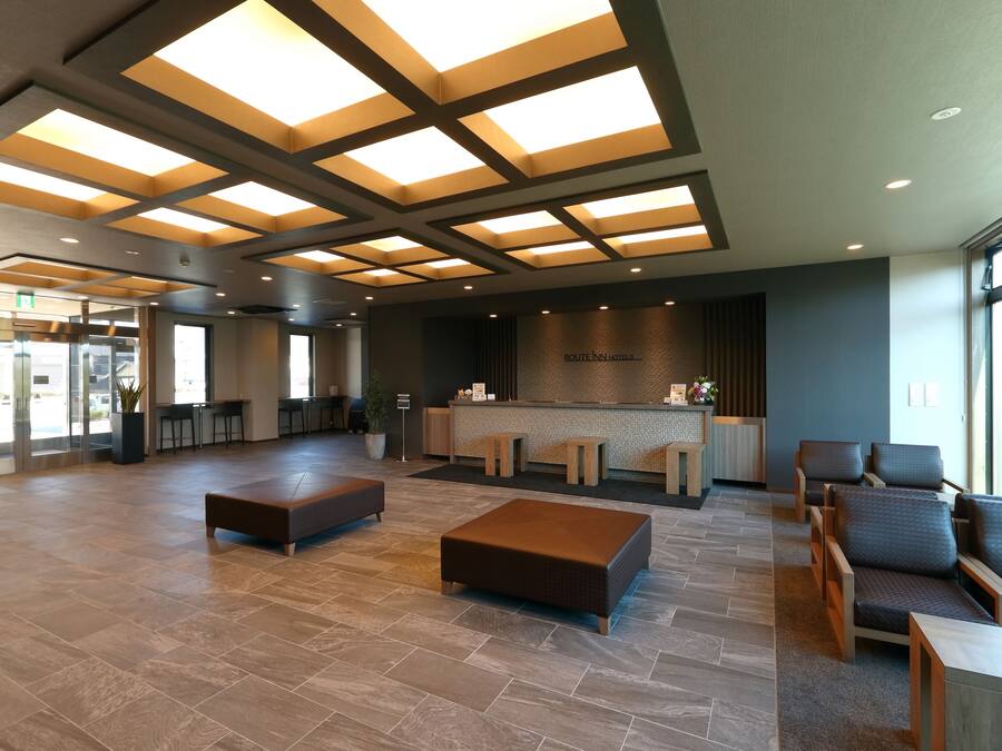 A spacious lobby with a reception desk, seating area, and a large window providing natural light.