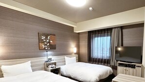 Een hotelkamer met twee bedden, een televisie, een bureau en een lamp.