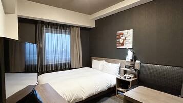 A hotel room with a bed, bedside table, lamp, and a TV.