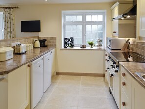 A compact kitchen with white cabinets, a built-in oven, a microwave, and a window with a view. - 3 bedroom accommodation in Spring Gardens, Frome (Spring Gardens, Frome)