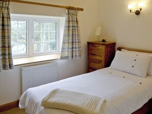A bedroom with a bed, a wooden dresser, a radiator, and a window with curtains. - 3 bedroom accommodation in Spring Gardens, Frome (Spring Gardens, Frome)