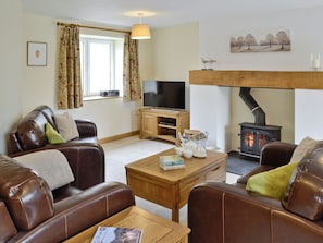 A cozy living room with leather sofas, a wooden coffee table, a television, and a wood-burning stove. - 3 bedroom accommodation in Spring Gardens, Frome (Spring Gardens, Frome)